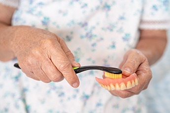 Woman brushing her dentures